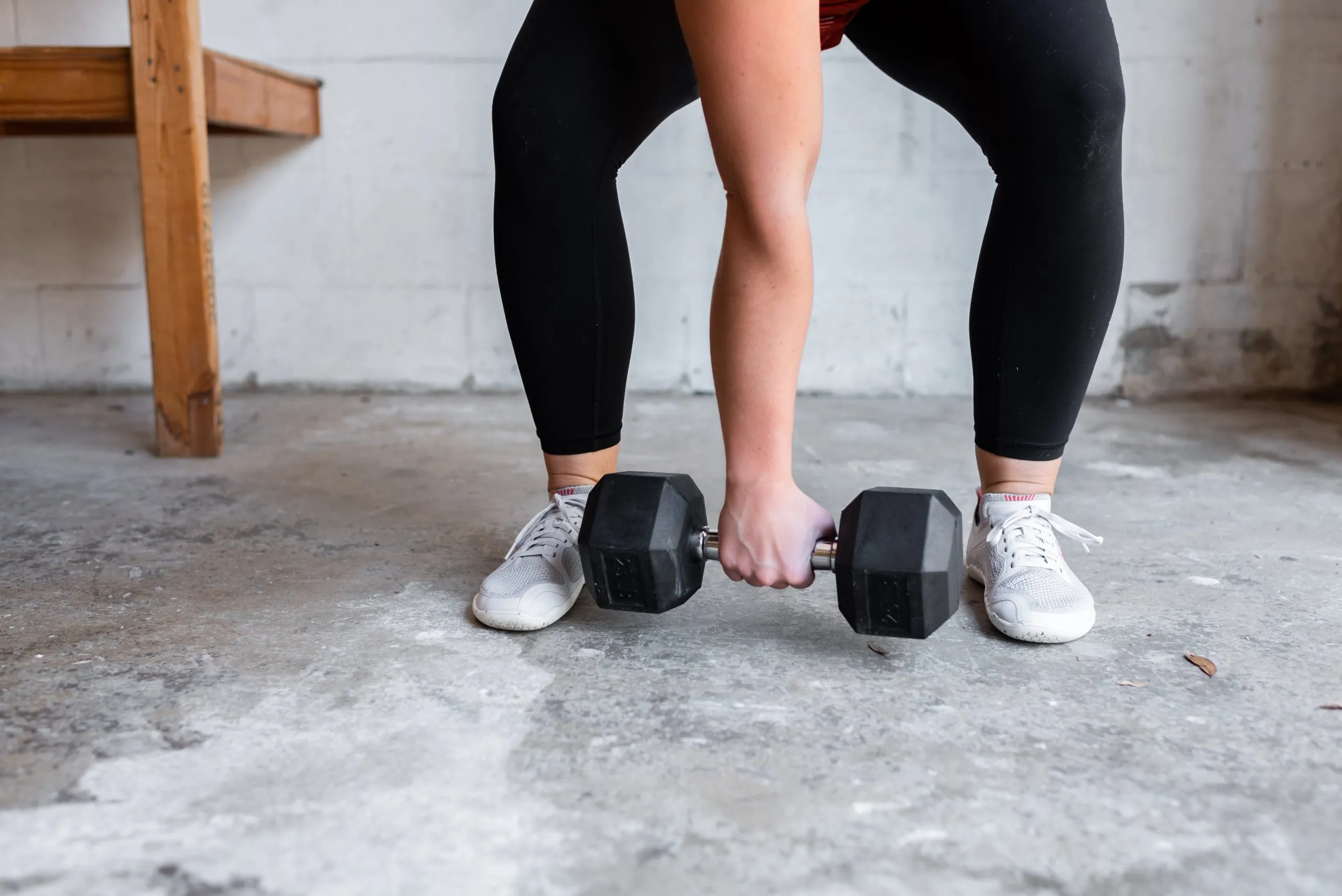 A photo of Dr. Jen Hosler holding a dumbbell near her feet.