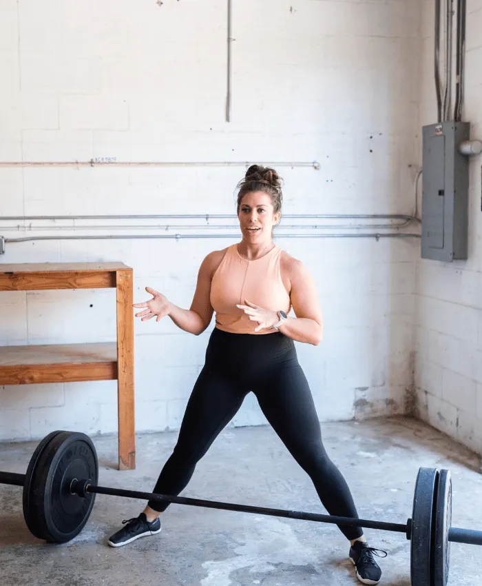 Untitled design (8)-min A photo of Dr. Jen Hosler standing with a barbell instructing the deadlift.